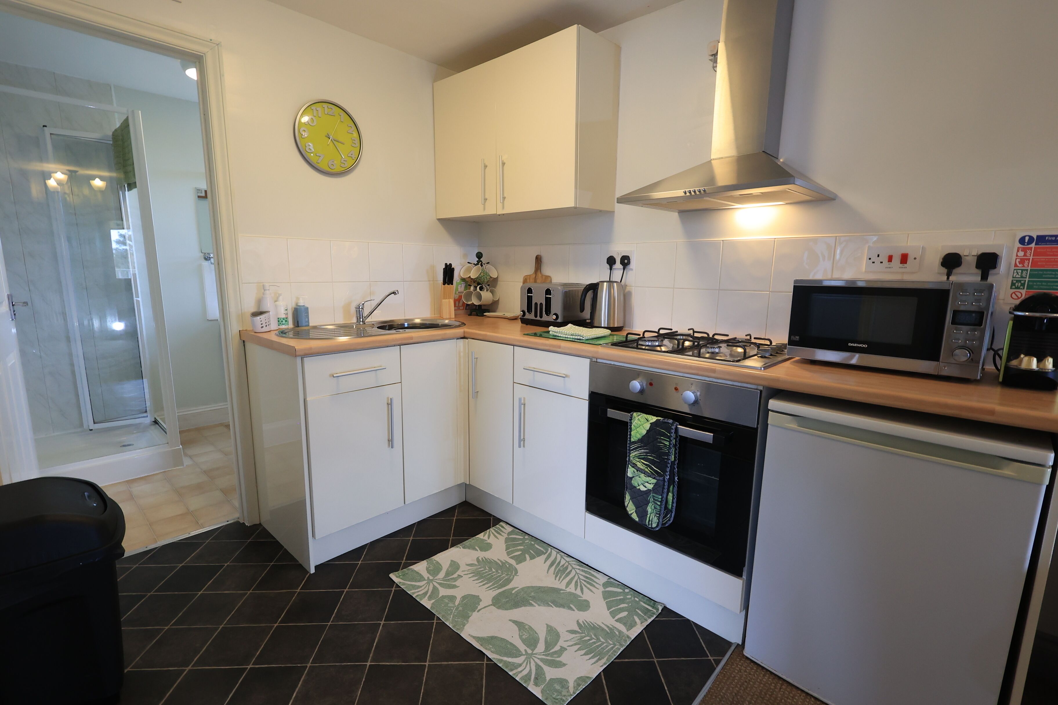 A compact kitchen with white cabinets, a microwave, a toaster, and a gas stove.