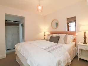 A bedroom with a bed, bedside lamps, a mirror, and a wardrobe. - Fosfelle Cottages (Bideford)