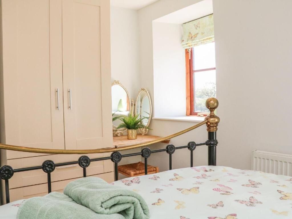 A bedroom with a bed, a wardrobe, a window with curtains, and a bedside table with a plant.