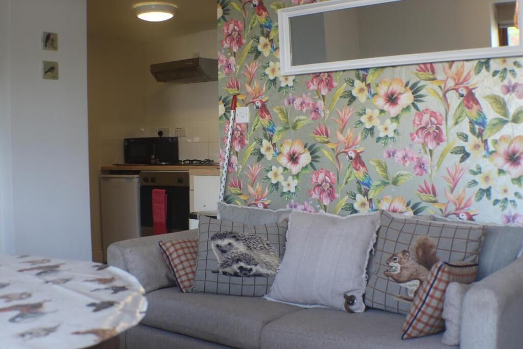 A living room with a sofa, a round table, and a floral-patterned wall.