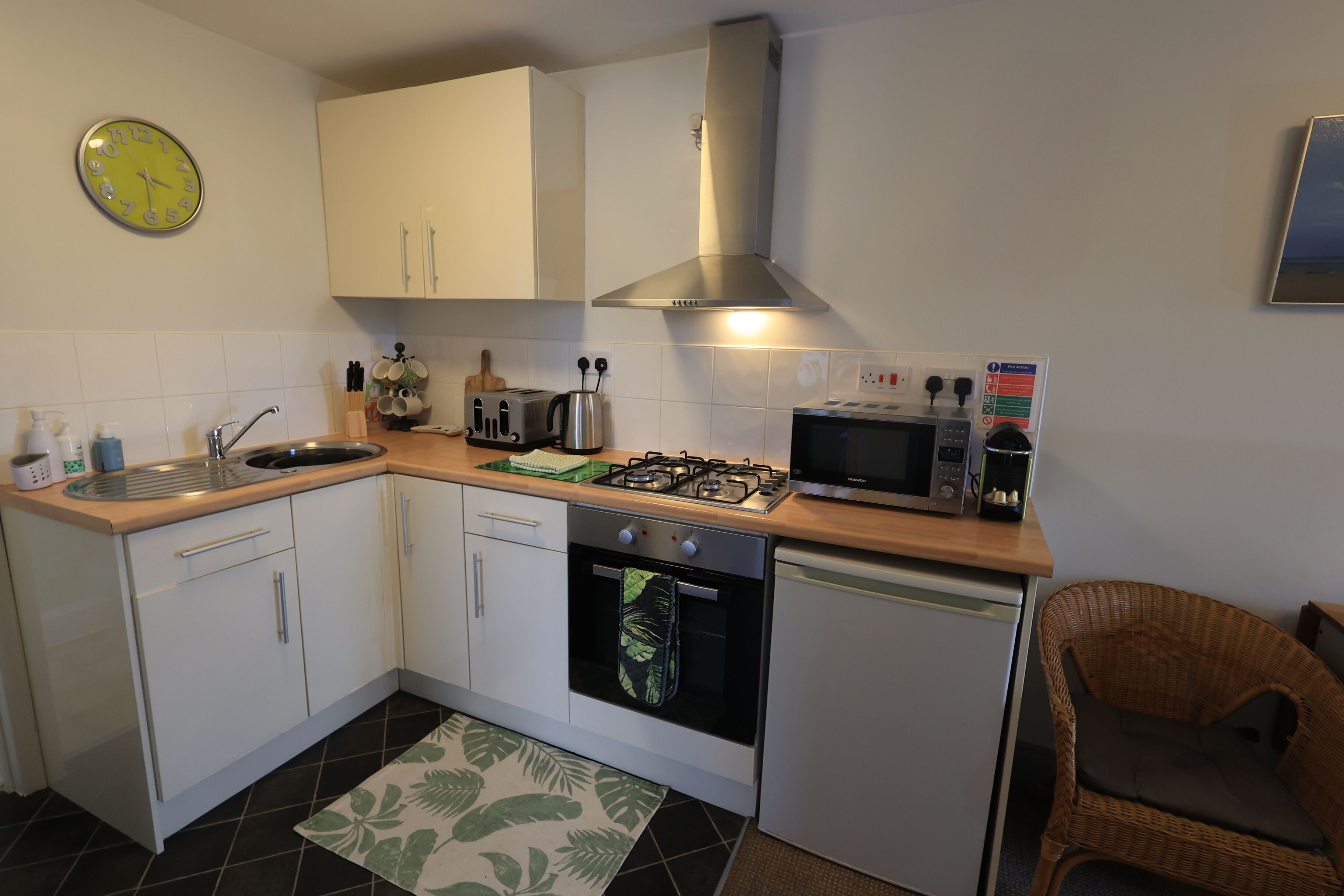 A compact kitchen with white cabinets, a gas stove, a microwave, and a sink.