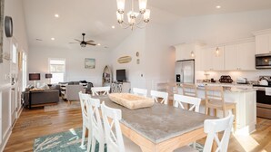 A spacious kitchen with white cabinetry, a central island, and pendant lighting. - The Teal Turtle: Beautiful, spacious home with easy beach access (Oak Island)