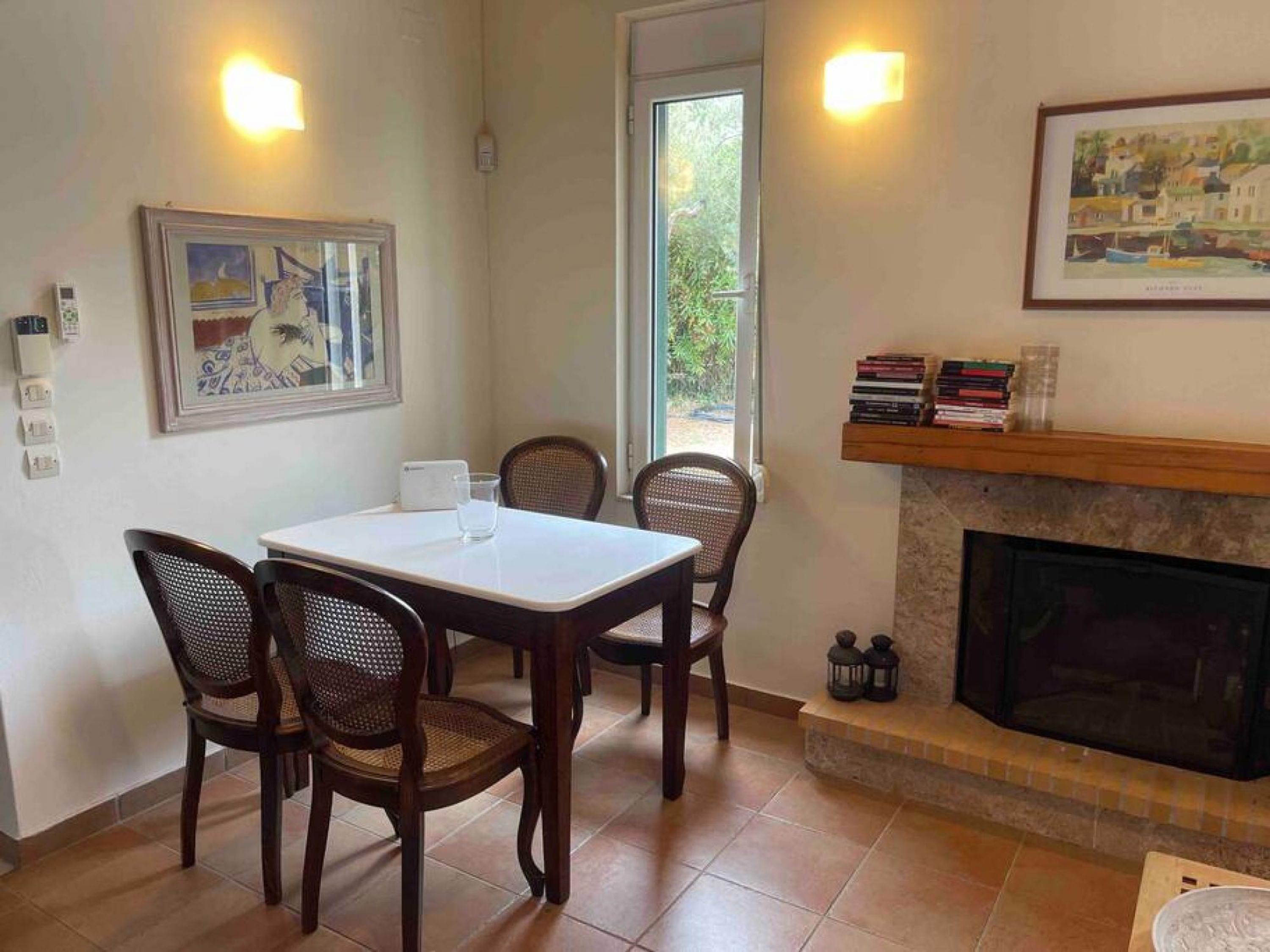 A dining area with a table and four chairs, a fireplace, and a framed picture on the wall.