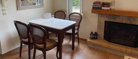 A dining area with a table and four chairs, a fireplace, and a framed picture on the wall.