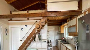A kitchen with a wooden staircase, a refrigerator, and a sink.