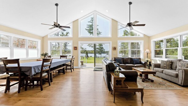 A spacious living room with a large dining table, sofas, and a view of a lake. - Two Homes: 1-Hot Tub; 2-Lakefront w/Dock, Big Yard (Pullman)