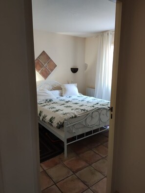 Un dormitorio con cama, estante en la pared y radiador.