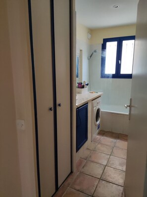 Un baño pequeño con lavadora, ducha y ventana.