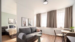 Una sala moderna con un sofá gris, una mesita redonda y un comedor con una silla.
