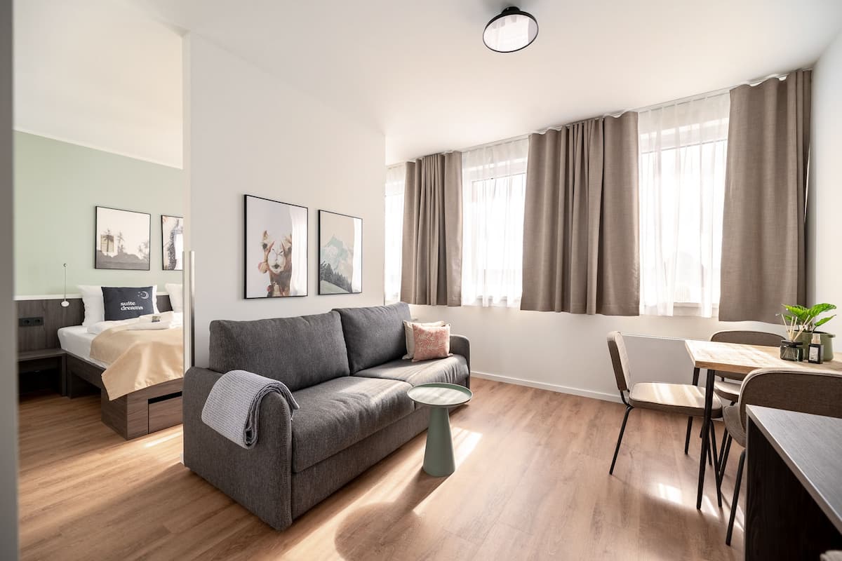 Ein modernes Wohnzimmer mit einem grauen Sofa, einem kleinen runden Tisch und einem Essbereich mit einem Stuhl.
