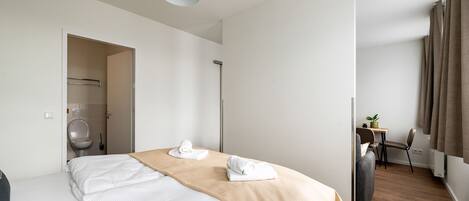 Une chambre d’hôtel moderne équipée d’un lit, d’un bureau et d’un espace douche.