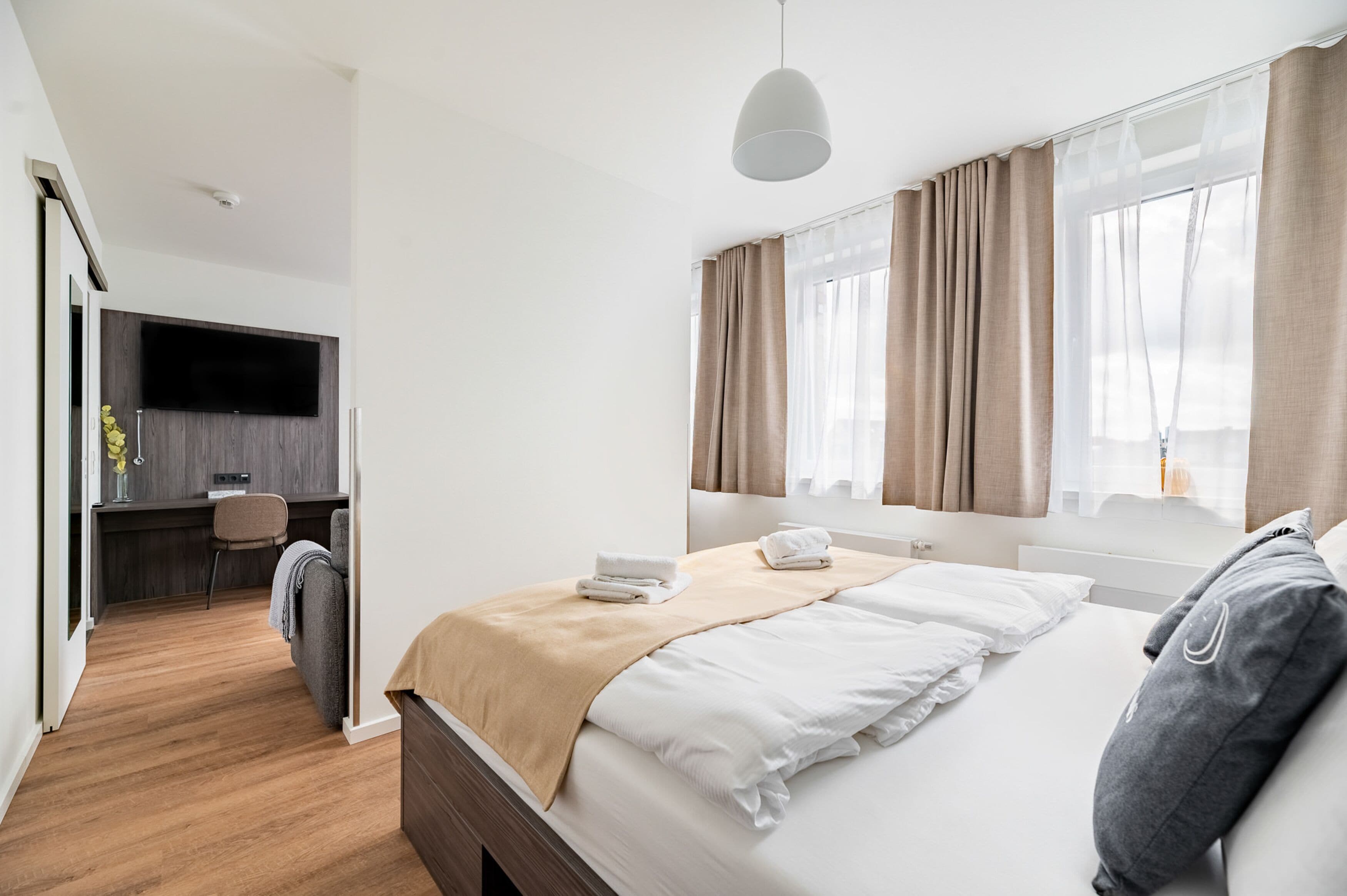 A modern hotel room with a bed, a desk, and a TV.