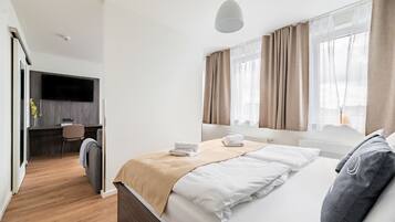 A modern hotel room with a bed, a desk, and a TV.