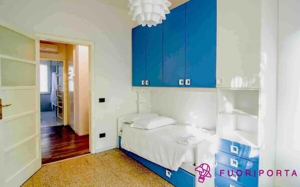 Cozy retreat with a bed, wardrobe, and ceiling light fixture.