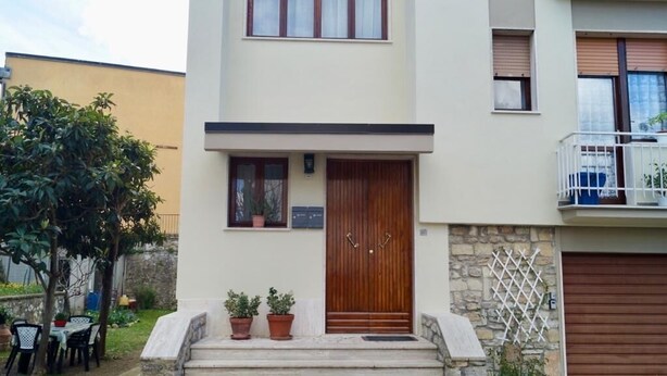 Un bâtiment à deux étages avec une porte en bois, des marches en pierre et un balcon.