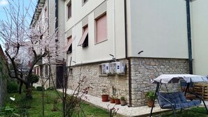 Un bâtiment en pierre doté d’un jardin, d’une chaise suspendue et de plantes en pot.