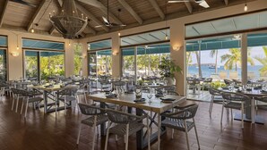 A spacious restaurant with high ceilings, large windows, and a view of the ocean. Tables are set with chairs and dining ware. - Beautiful Secluded Island Getaway (St. Thomas)