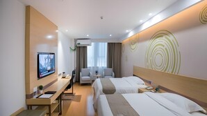 Una habitación de hotel con dos camas, un escritorio, un televisor y una zona de estar.