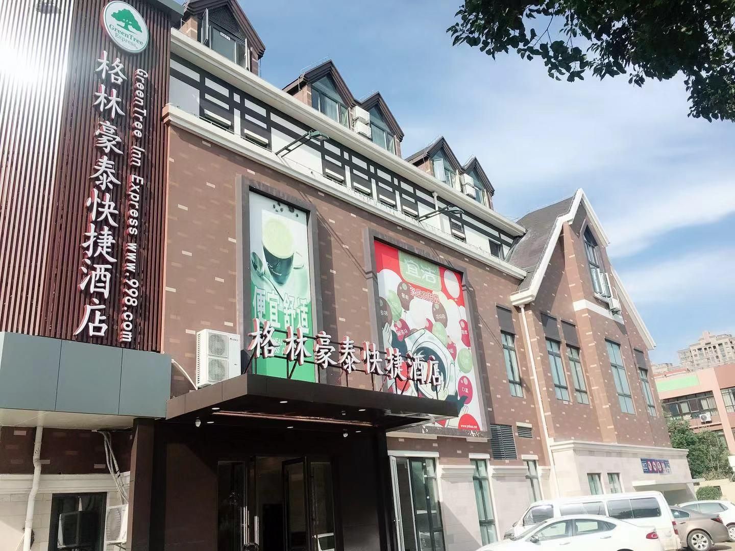 A hotel with a prominent sign for GreenTree Express and a large banner advertising a tea experience.