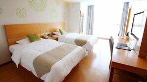 Habitación de hotel con dos camas, un escritorio de madera y un ventanal con cortinas.