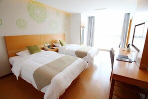 Habitación de hotel con dos camas, un escritorio de madera y un ventanal con cortinas.