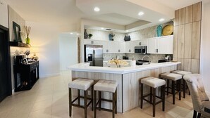 A modern kitchen with a central island, bar stools, and a built-in oven.