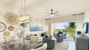 A modern living room with a dining area, a ceiling fan, and a view of the outdoors.