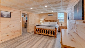 A wooden cabin-style bedroom with a bed, bedside table, and a large window. - Wild Creek Cabin (Mineral Bluff)