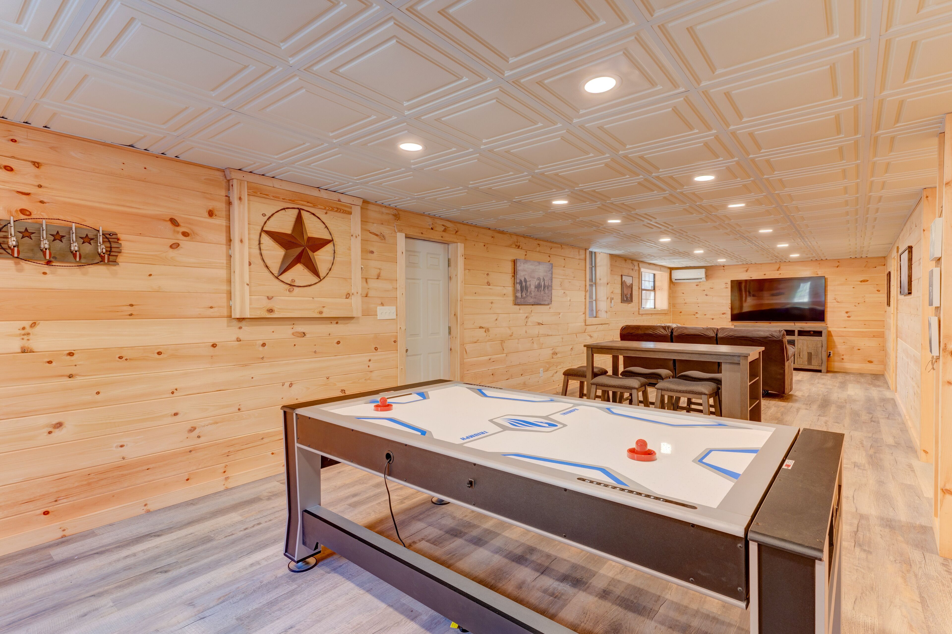 Une pièce au plancher en bois, avec un baby-foot, une décoration en forme d’étoile et un téléviseur fixé au mur.