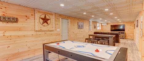 Une pièce au plancher en bois, avec un baby-foot, une décoration en forme d’étoile et un téléviseur fixé au mur.