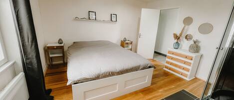 A bedroom with a bed, bedside tables, a dresser, and a mirror on the wall.