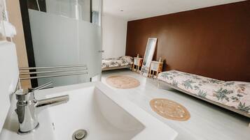 A modern bathroom with a large mirror, a white sink, and a bed with floral bedding.