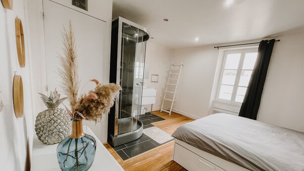 A bedroom with a bed, a wardrobe, a bathroom with a glass door, and a window with curtains. - cottage of the poste (Crouay)