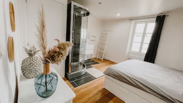 A bedroom with a bed, a wardrobe, a bathroom with a glass door, and a window with curtains.