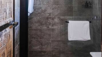 Un baño con cabina de ducha de vidrio, un inodoro blanco y un perchero para toallas.