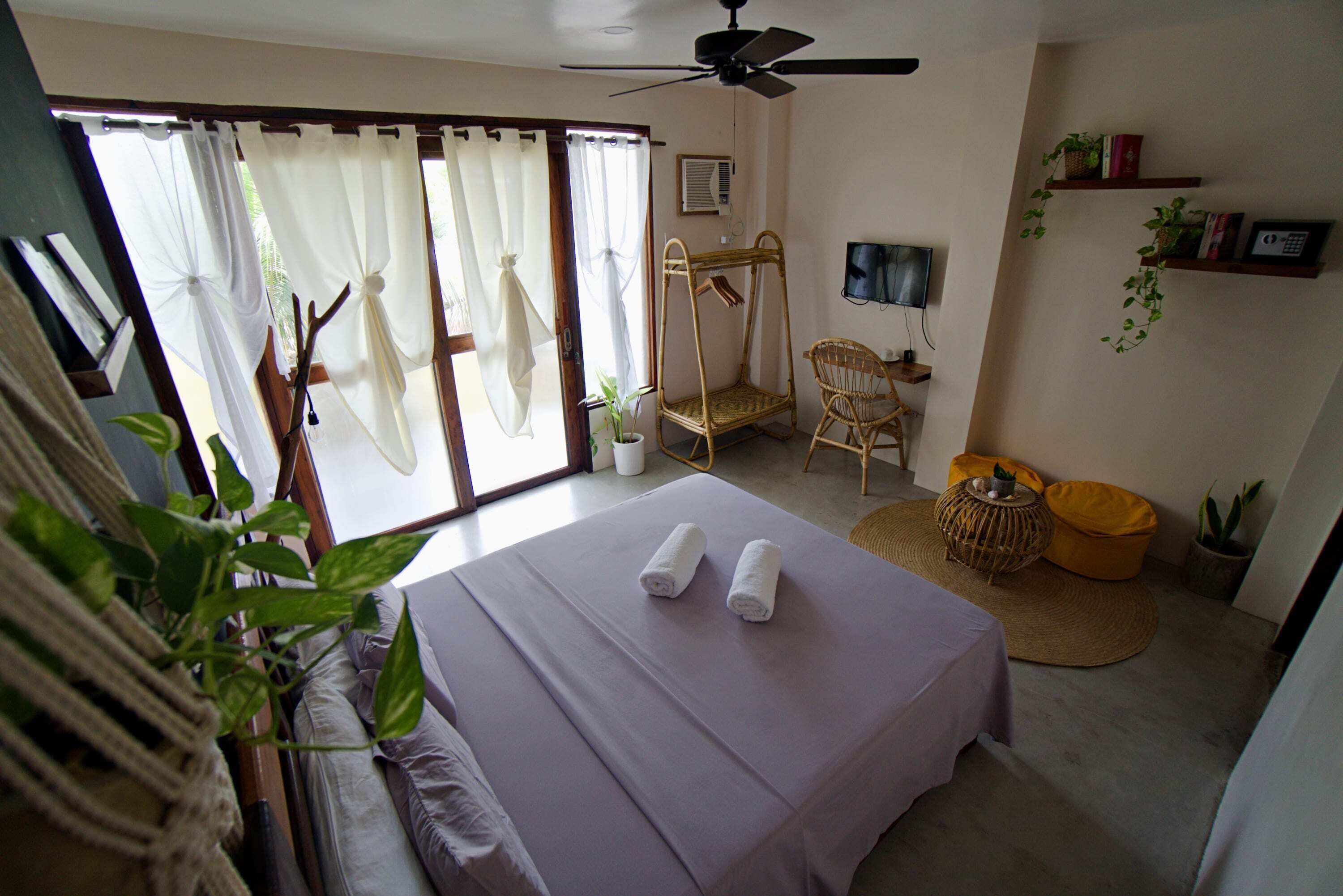 A bedroom with a bed, a ceiling fan, a TV, and a sliding door.