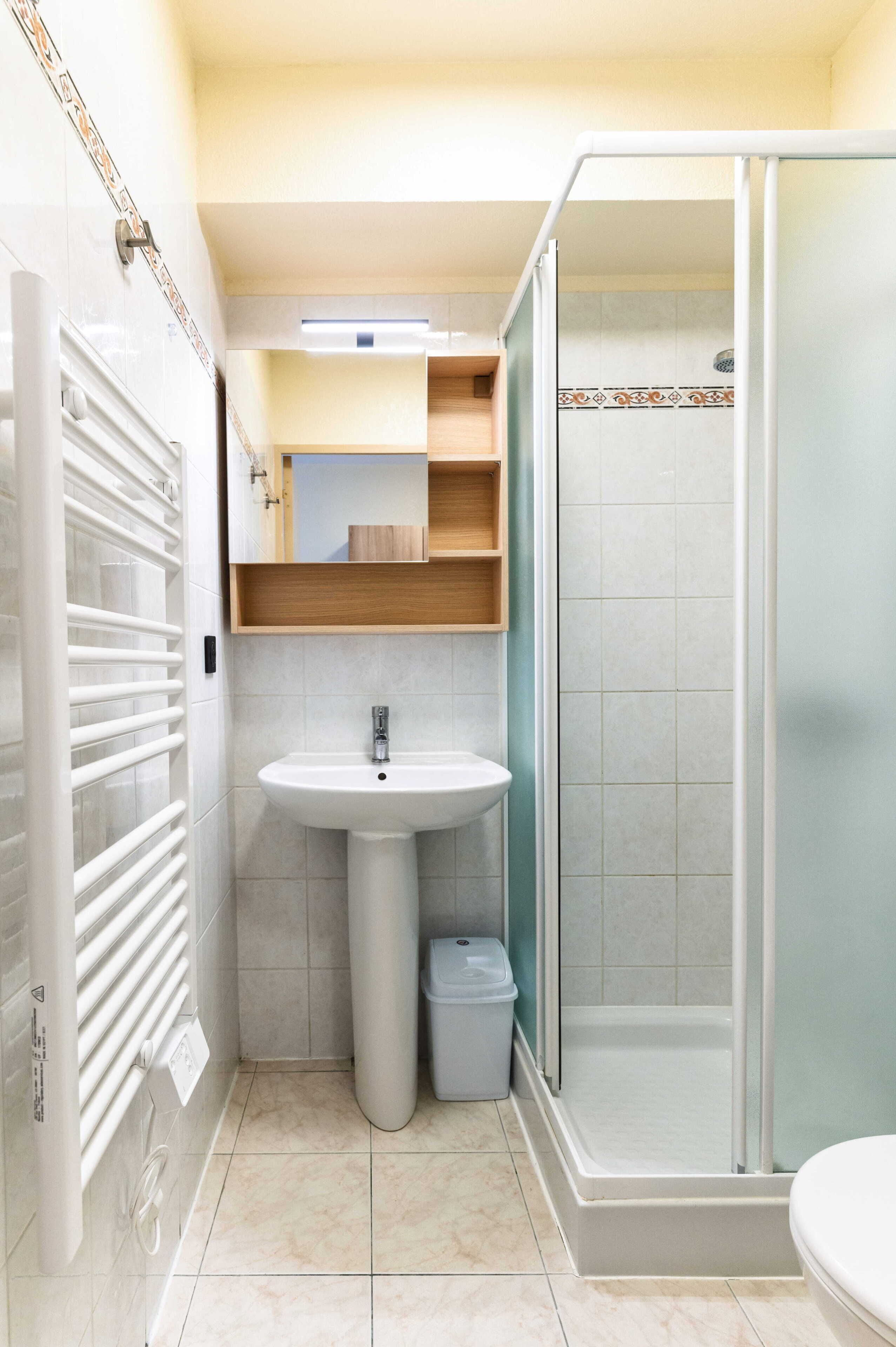 Un baño pequeño con lavamanos pedestal, cabina de ducha e inodoro.
