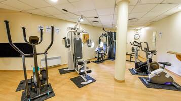 A gym with various exercise machines, mats, and a clock on the wall.