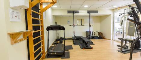 A gym with exercise equipment, a wooden ladder, and a wall-mounted air conditioning unit.