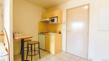 A compact kitchen with a microwave, sink, and a small dining area with stools.