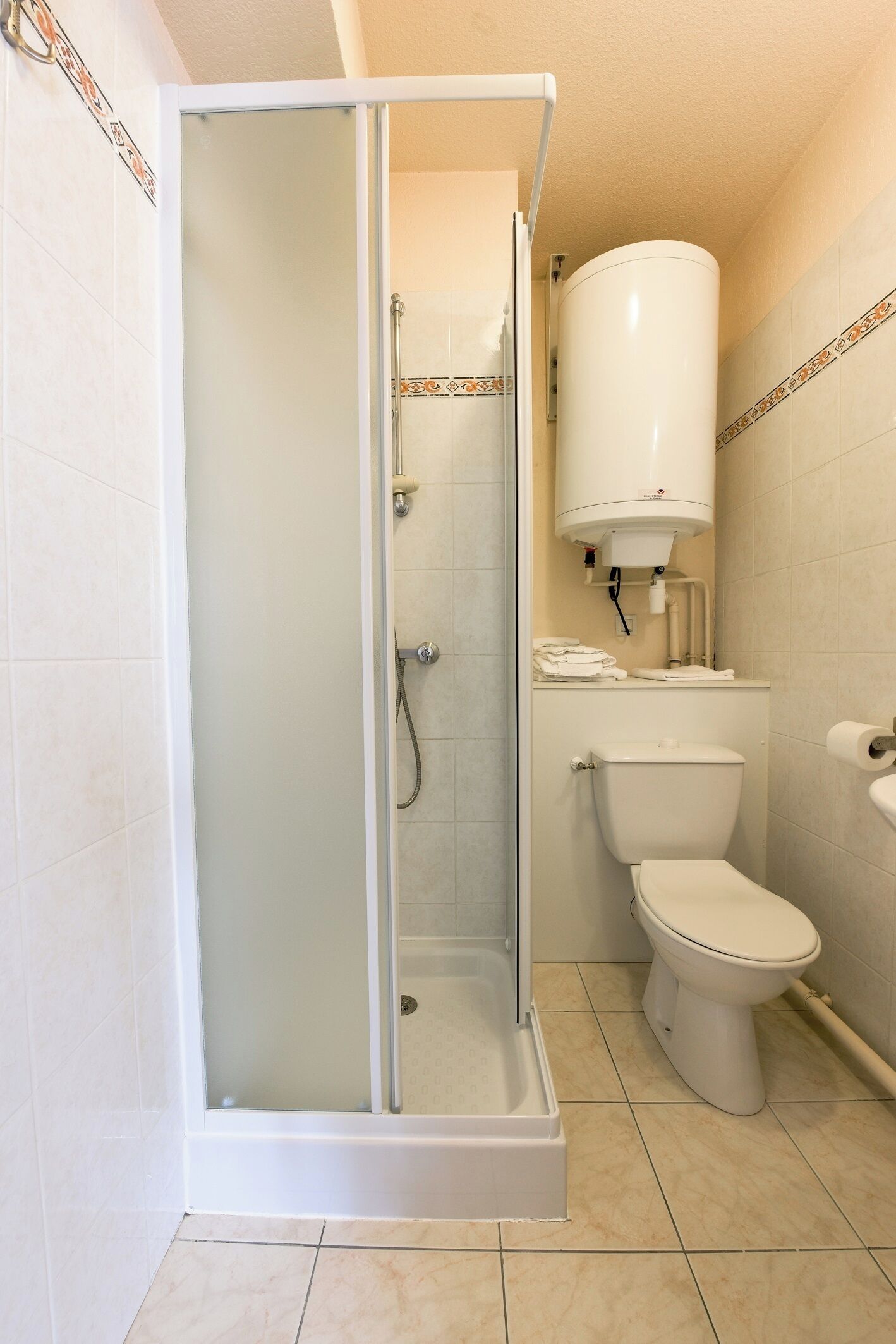 A bathroom with a glass-enclosed shower, a toilet, and a white water heater.