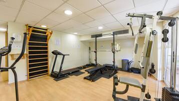 Une salle de sport équipée de matériel d’exercice, d’un tapis de course et d’un banc de musculation.