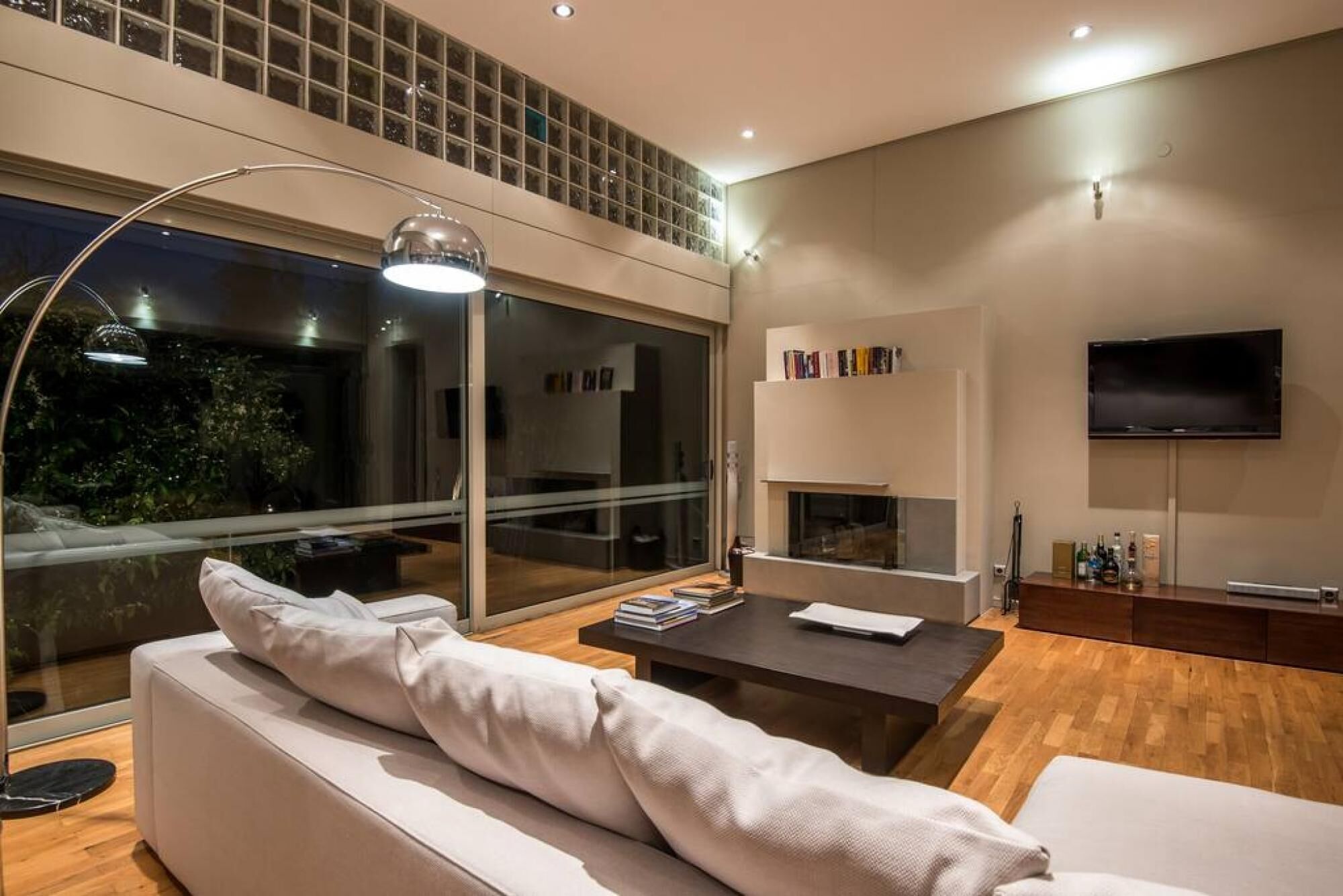 Un salon moderne avec un canapé, une table basse, une cheminée et un téléviseur fixé au mur.