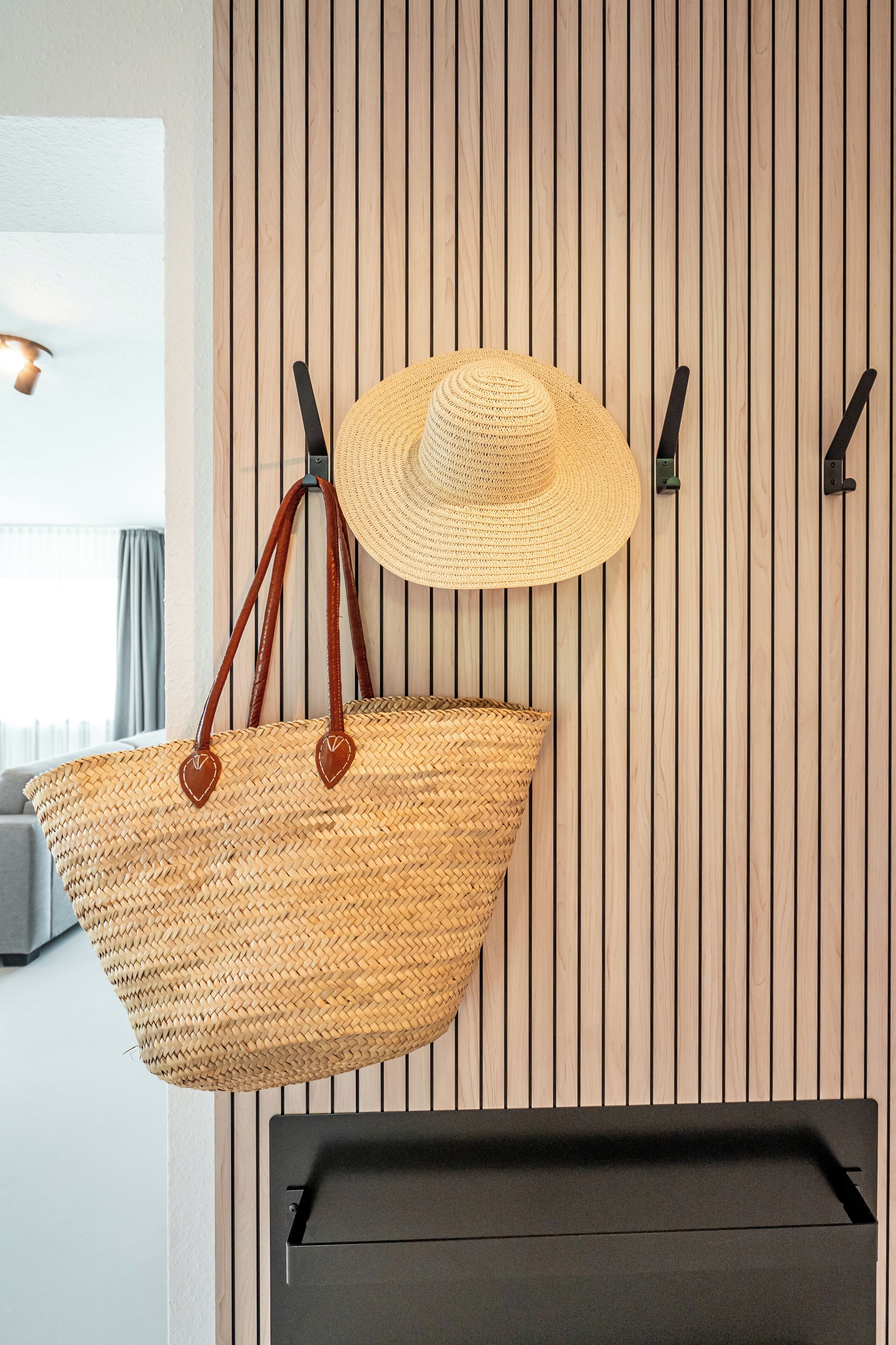 Una habitación con una cesta grande tejida colgada en una pared con listones de madera verticales.