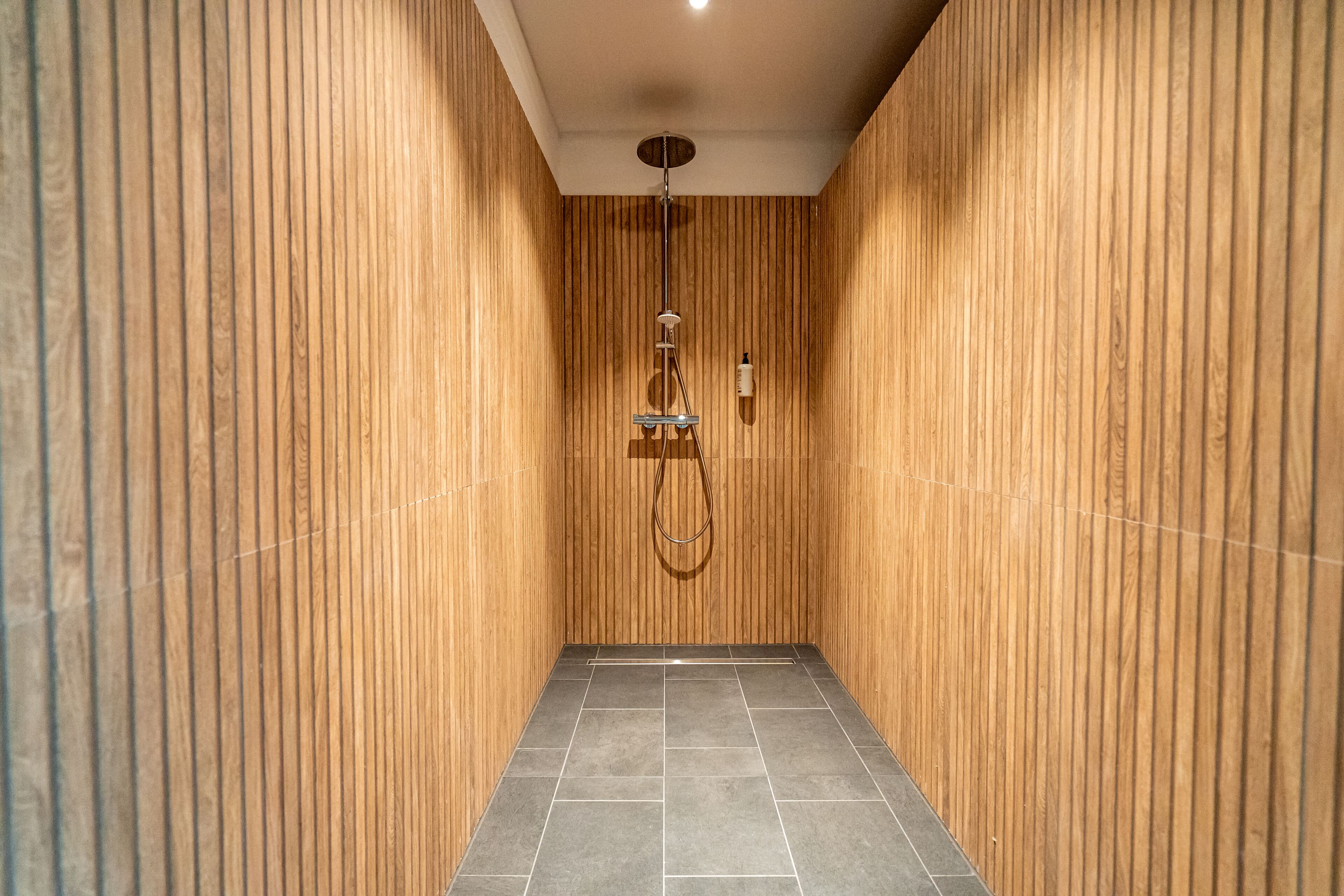 Un baño moderno con paneles de madera y suelo de baldosas.