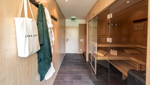 A hallway with wooden lockers, a glass partition, and a door leading to a sauna area. - stuub hinterzarten (Breitnau)
