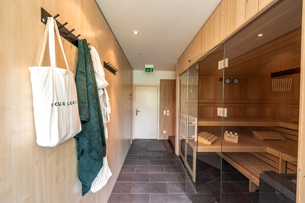 A hallway with wooden lockers, a glass partition, and a door leading to a sauna area. - stuub hinterzarten (Breitnau)