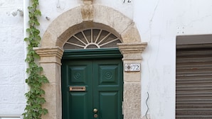A green double door with a stone archway, number 72, and two potted plants on either side. - Viasarnelli72 b&b (Polignano a Mare)