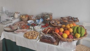 A buffet table with various food items, including fruits, pastries, and a pie. - Viasarnelli72 b&b (Polignano a Mare)