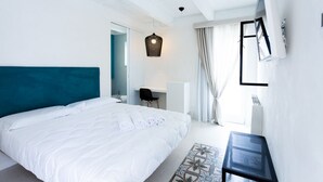 A modern bedroom with a large bed, a desk, and a TV mounted on the wall. - Viasarnelli72 b&b (Polignano a Mare)